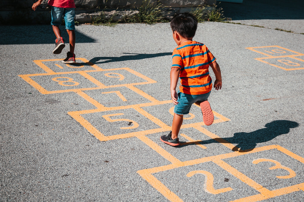 Children playing hopscotch outside of school.